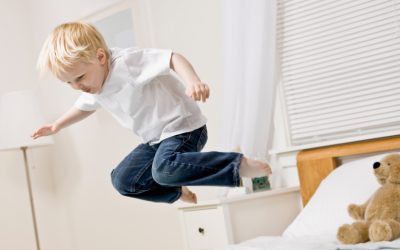 Kleiner Junge springt auf einem Lattenrost und einer Matratze